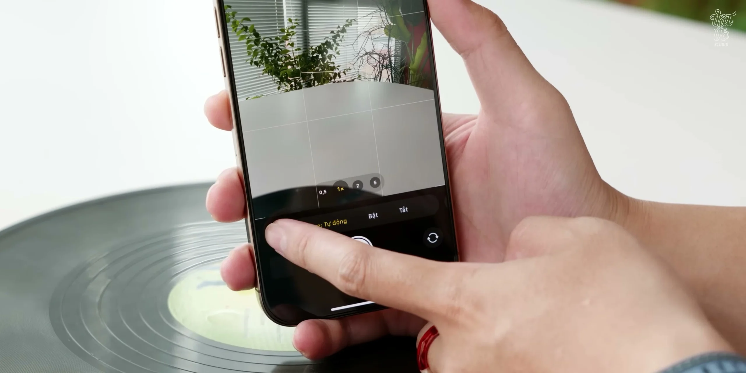 Ngón tay trỏ đang nhấn vào nút Camera Control trên cạnh phải của iPhone 16 Pro Max để điều chỉnh thanh trượt trên màn hình tại giây 00:04:59